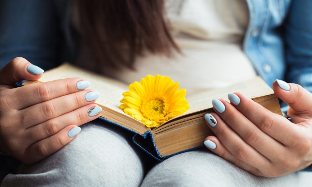 Girl's hands on a book with a yellow flower